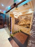Un vestíbulo con pared de mármol, una gran obra de arte circular e iluminación moderna.