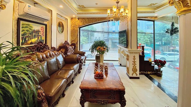 A luxurious lobby with a leather sofa, a wooden coffee table, and a large window offering a view of the street. - Nam Cuong X Hotel (Hanoi)