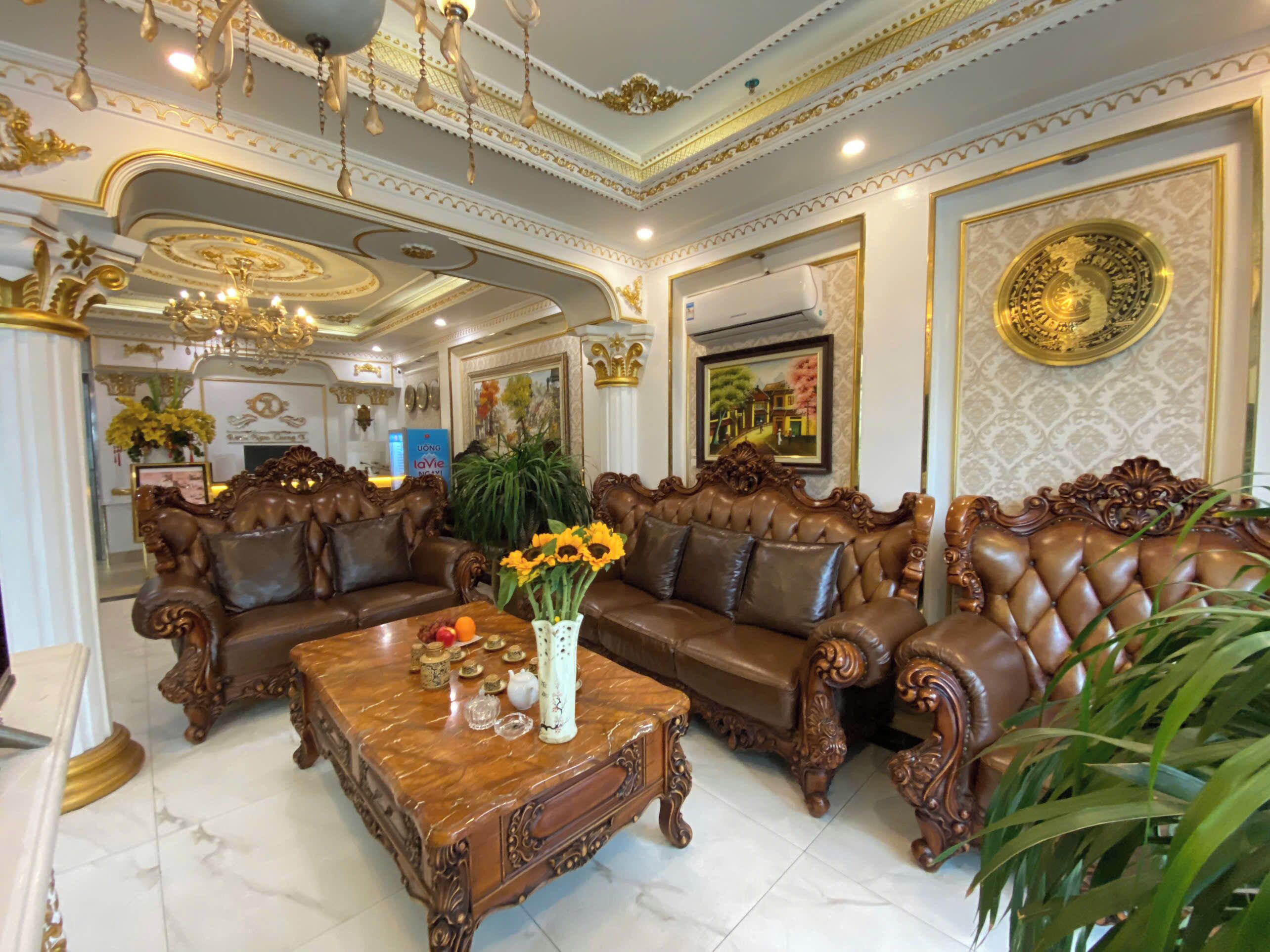 A luxurious living room with ornate furniture, a marble coffee table, and decorative elements like a chandelier and framed artwork.