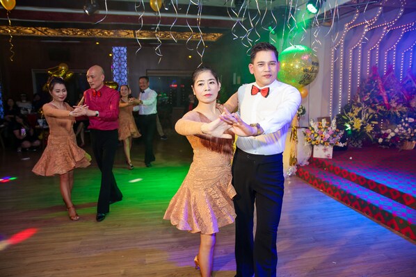 A dance floor with a patterned carpet and a floral arrangement in the background. - Long Anh Hotel (Hac Thanh)