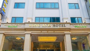 Un hotel alto con una entrada imponente, varios pisos y una vista despejada del cielo.