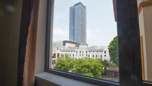 Vista desde una ventana de un edificio alto de diseño moderno, un edificio blanco de varios pisos en primer plano y algo de vegetación.
