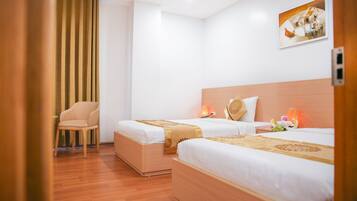 Habitación de hotel con dos camas, piso de madera, una silla y un cuadro en la pared.