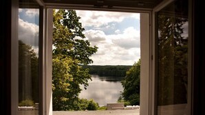 Una ventana con vista a un lago rodeado de árboles.
