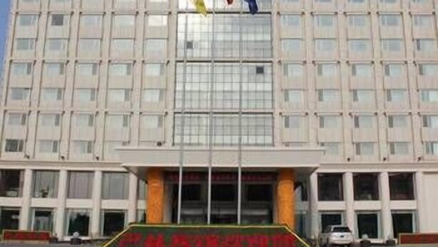 A multi-story building with a symmetrical facade, large windows, and a central entrance with a green signboard. - Balin Hotel (Chifeng)