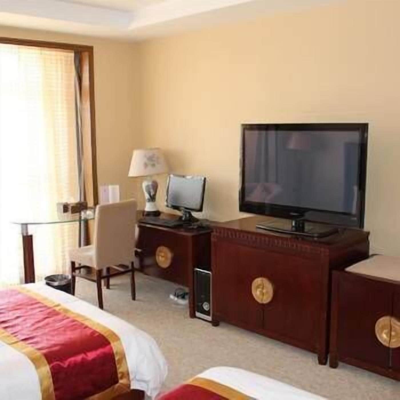 A hotel room with a bed, a desk with a computer, a television, and a chair.