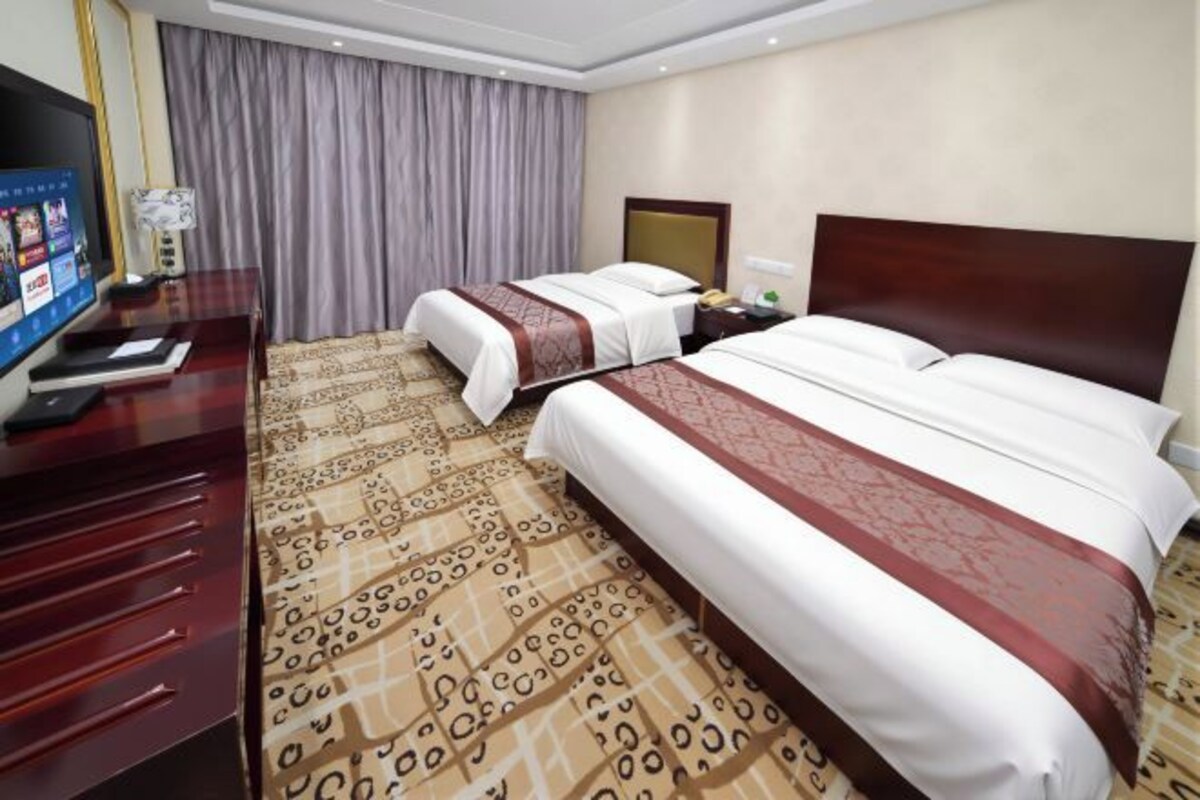 A hotel room with two beds, a desk with a computer, and a television.
