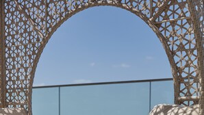 A wicker lounge chair with a view of the ocean, a glass of water, and a fruit platter on a table. - Mandarin Oriental Jumeira, Dubai (Dubai)