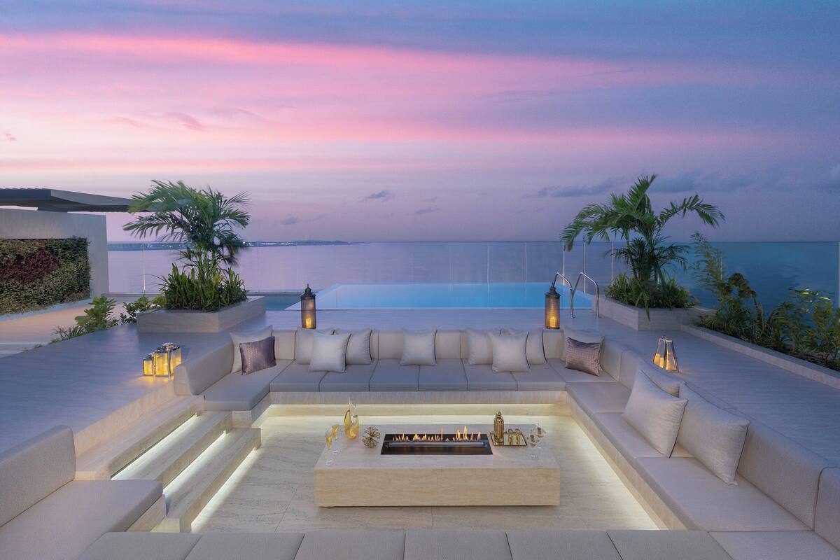 An outdoor seating area with a fire feature, cushioned seating, and ambient lighting.
