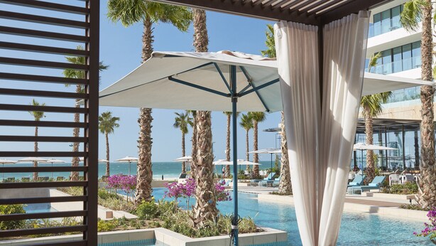 A poolside area with lounge chairs, a pergola, and a view of the ocean. - Mandarin Oriental Jumeira, Dubai (Dubai)