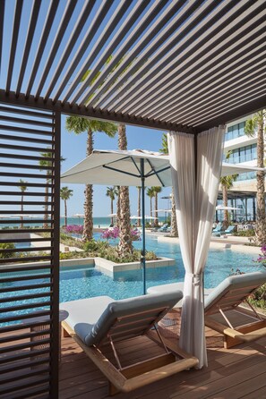 A poolside area with lounge chairs, a pergola, and a view of the ocean. - Mandarin Oriental Jumeira, Dubai (Dubai)