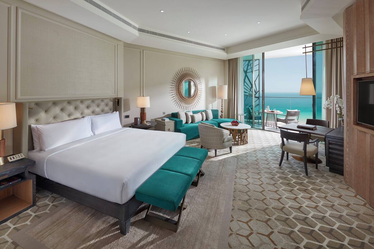 A hotel room with a large bed, a sofa, a small table, and a TV.