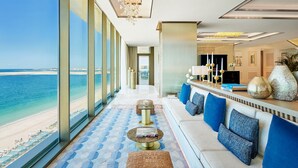 A hotel lobby with a view of the beach, a seating area with blue cushions, and a bar with decorative items. - Mandarin Oriental Jumeira, Dubai (Dubai)