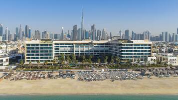 Un hôtel avec vue sur la plage, plusieurs étages et, en arrière-plan, le panorama de la ville.