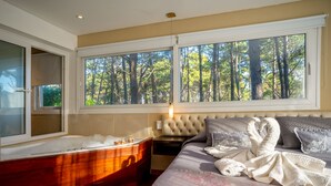A bedroom with a large window, a bathtub, and a bed with towels. - Mizu Hotel Boutique (Mar de Las Pampas)