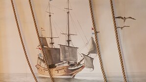 Een gezellige zithoek met twee leren banken, een klein rond tafeltje met een kaars, en touwen die van het plafond hangen.