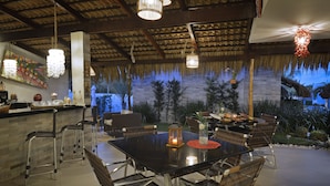 An outdoor dining area with a table set for four, surrounded by wicker chairs, and a bar area with stools. - Oasis Tajaja (Conde)