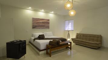 Quarto moderno com cama, mesa de cabeceira, banco e sofá.