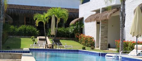 Una piscina al aire libre, sillones reclinables de piscina