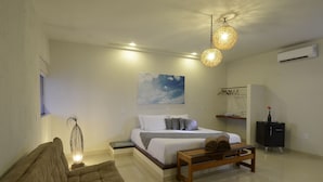 A bedroom with a bed, bedside table, hanging light fixture, and a painting on the wall. - Oasis Tajaja (Conde)