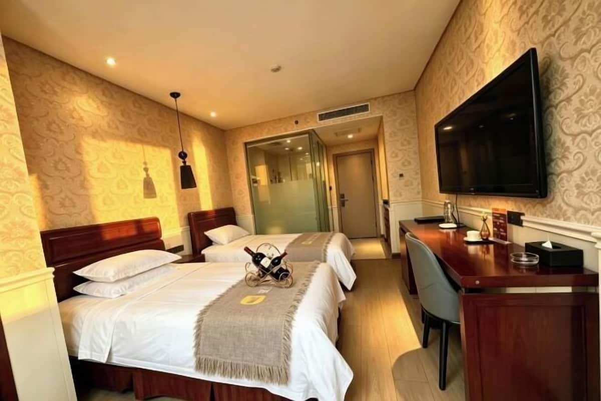 Ein Hotelzimmer mit zwei Betten, einem Schreibtisch, einem Flachbildfernseher und einer Minibar.