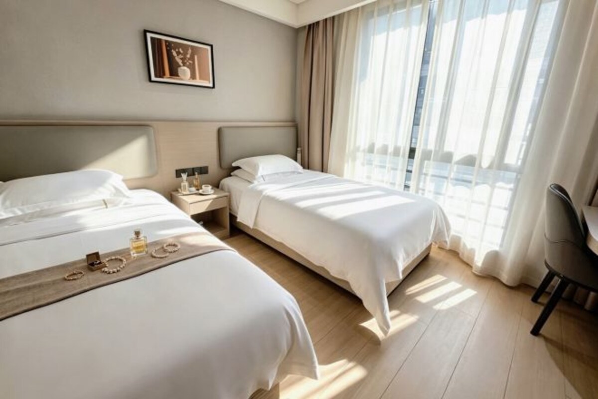 A hotel room with two beds, a nightstand, a desk, and a chair.