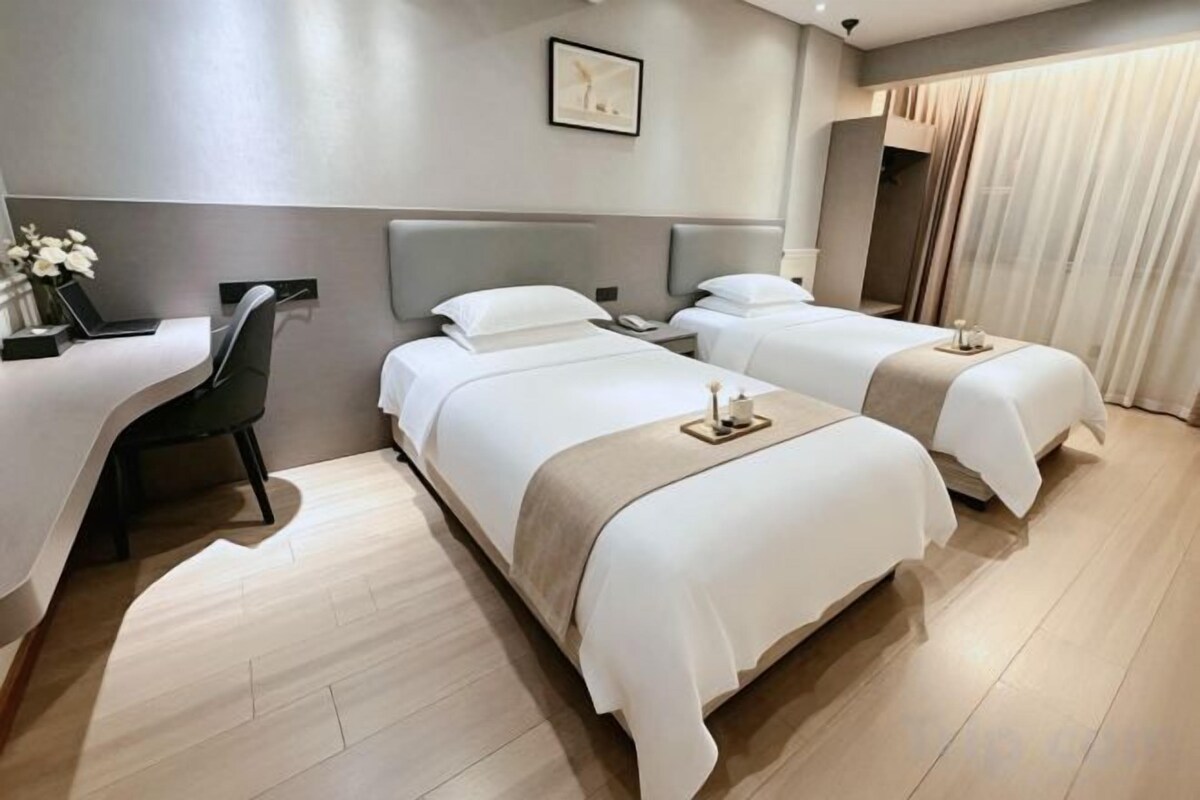 A hotel room with two beds, a desk, and a chair.