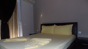 Ein ordentlich bezogenes Bett mit einem gefalteten Handtuch, einem Nachttisch und einer wandmontierten Klimaanlage.