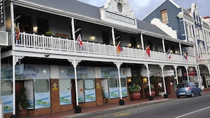 Un hotel histórico con balcón, varias banderas y tiendas, incluyendo una tienda llamada 'Town Store' y un restaurante llamado 'Central Hotel'.