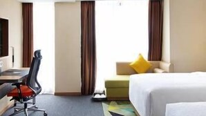 A hotel room with a desk, chair, two beds, a sofa, and a view of the outdoors. - Hampton by Hilton Chengdu Waishuangnan (Chengdu)