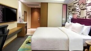 A hotel room with a bed, a TV, a desk, and a colorful rug. - Hampton by Hilton Chengdu Waishuangnan (Chengdu)