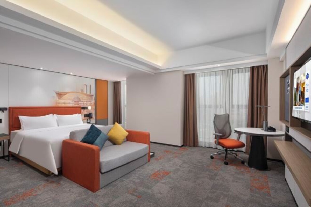 A hotel room with a bed, a sofa, a desk, and a chair.