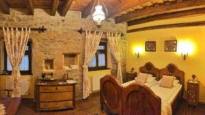 A rustic bedroom with a wooden bed, stone walls, and a vintage sewing machine. - Casa Bertha (Sighisoara)