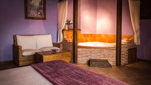 Una habitación con cama, sofá de mimbre, una mesita y una bañera.