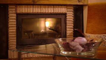 A fireplace with a glass table in front, a brick wall, and a wooden ceiling.