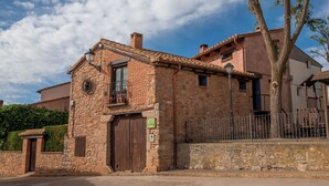 Un edificio rústico de piedra con diseño tradicional, que cuenta con una puerta de madera grande y un balcón pequeño.