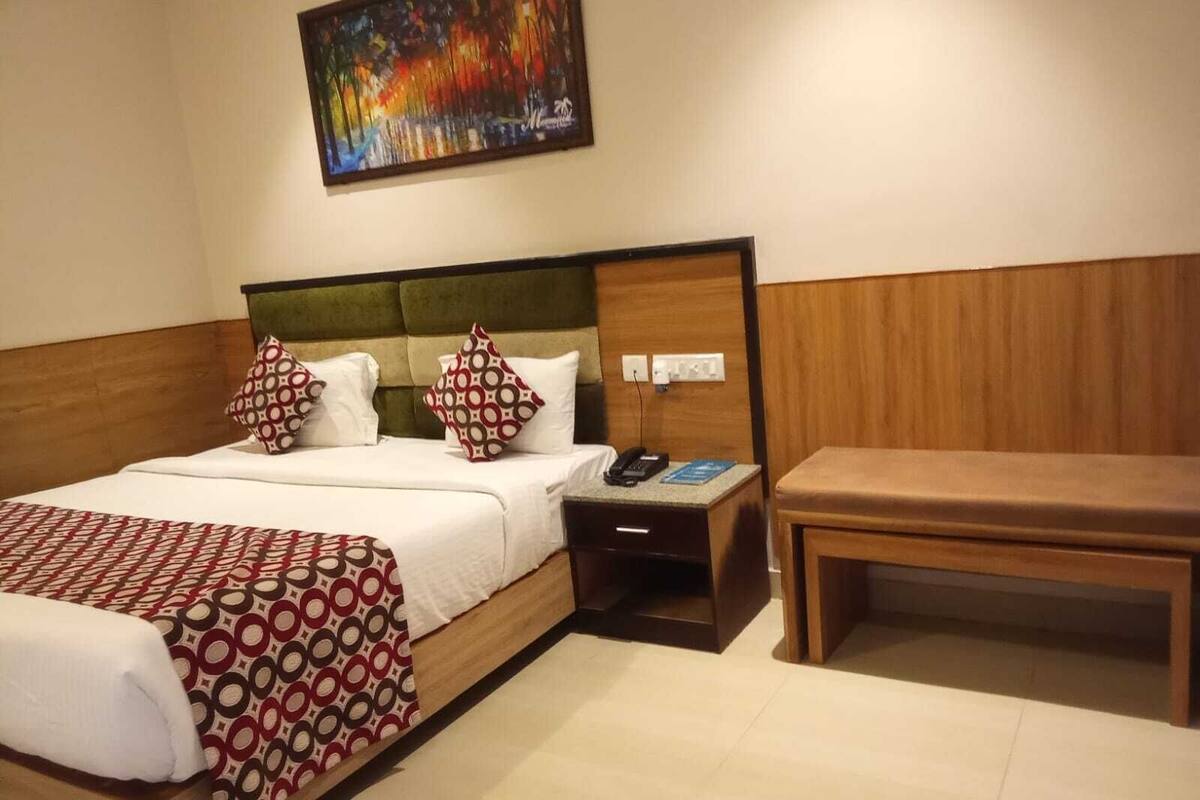 Une chambre d’hôtel avec un lit, une table de chevet et un tableau au mur.