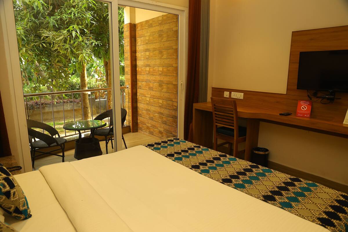 Une chambre d’hôtel comprenant un lit, un bureau avec une chaise, une télévision et un balcon avec des chaises et une table.