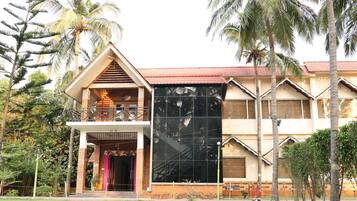 A building with a balcony, a large reflective glass facade, and palm trees.