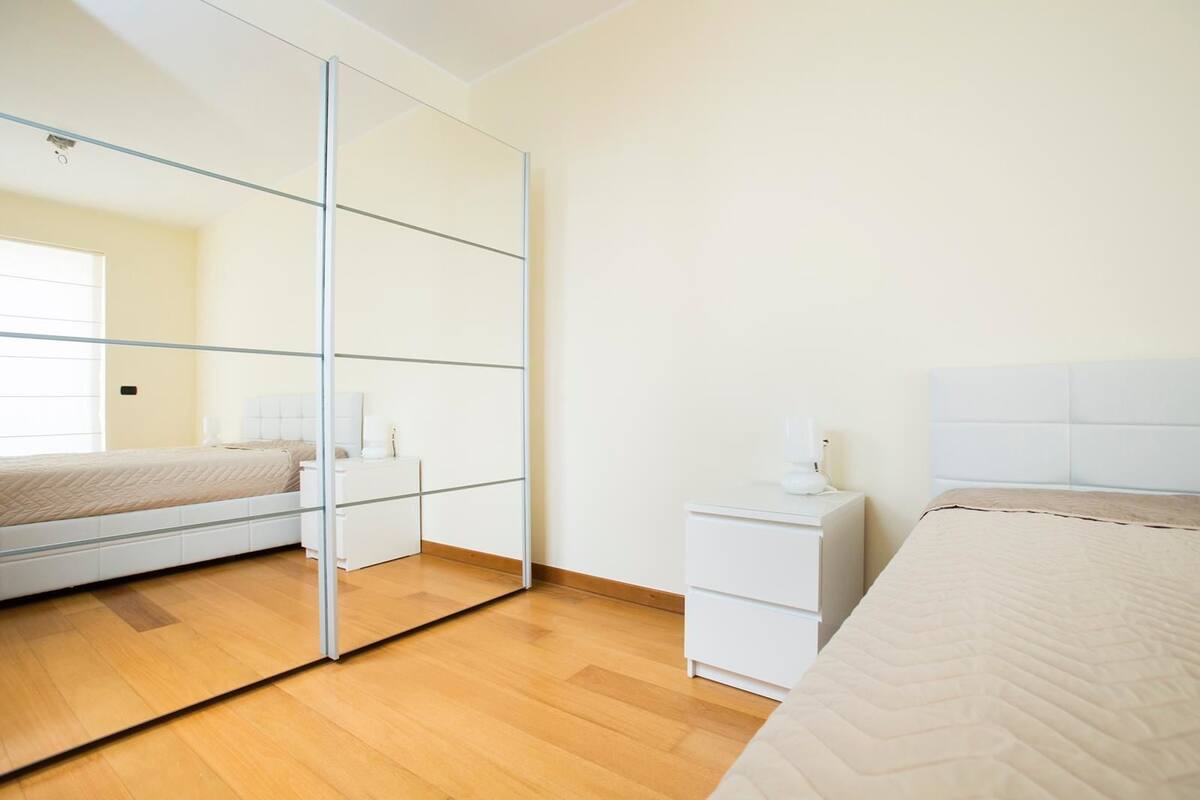 Ein Schlafzimmer mit Bett, Nachttisch, Spiegel und Kleiderschrank.