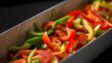 A rectangular metal tray filled with sliced bell peppers in various colors.