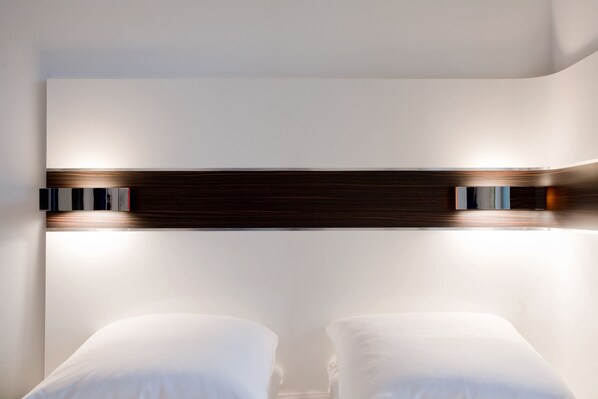A modern hotel room with a large bed, a wooden headboard, and a wall-mounted light fixture. - Wakeup Copenhagen Bernstorffsgade (Copenhagen)