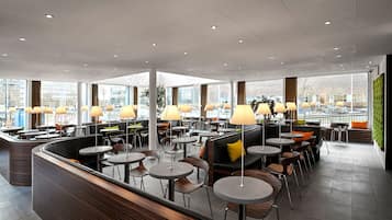A modern indoor seating area with round tables, chairs, and ambient lighting.