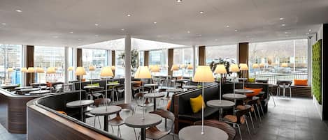 A modern indoor seating area with round tables, chairs, and ambient lighting.