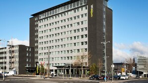 Ett hotell med flera våningar och modern design, med en tydlig skylt med texten ”väck” på fasaden.