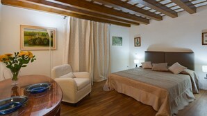 A bedroom with a bed, a chair, a table with blue plates, and a painting on the wall. - A characteristic and comfortable location in the heart of Florence's (Firenze)
