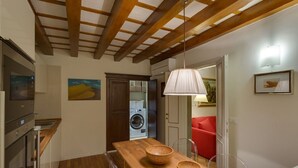 A modern kitchen with wooden beams, a wooden dining table with bowls, a washing machine, and a red chair. - A characteristic and comfortable location in the heart of Florence's (Firenze)