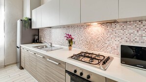 A modern kitchen with white cabinets, a gas stove, a sink, and a tiled backsplash. - Apartments Florence - Ghibellina Loft (Firenze)