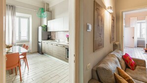 A modern kitchen with white cabinets, a dining table with chairs, and a hanging light fixture. - Apartments Florence - Ghibellina Loft (Firenze)