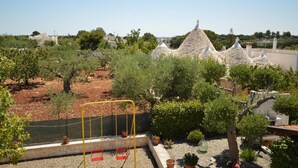 Zona residencial con casas de techo de piedra, un parque infantil y abundante vegetación.